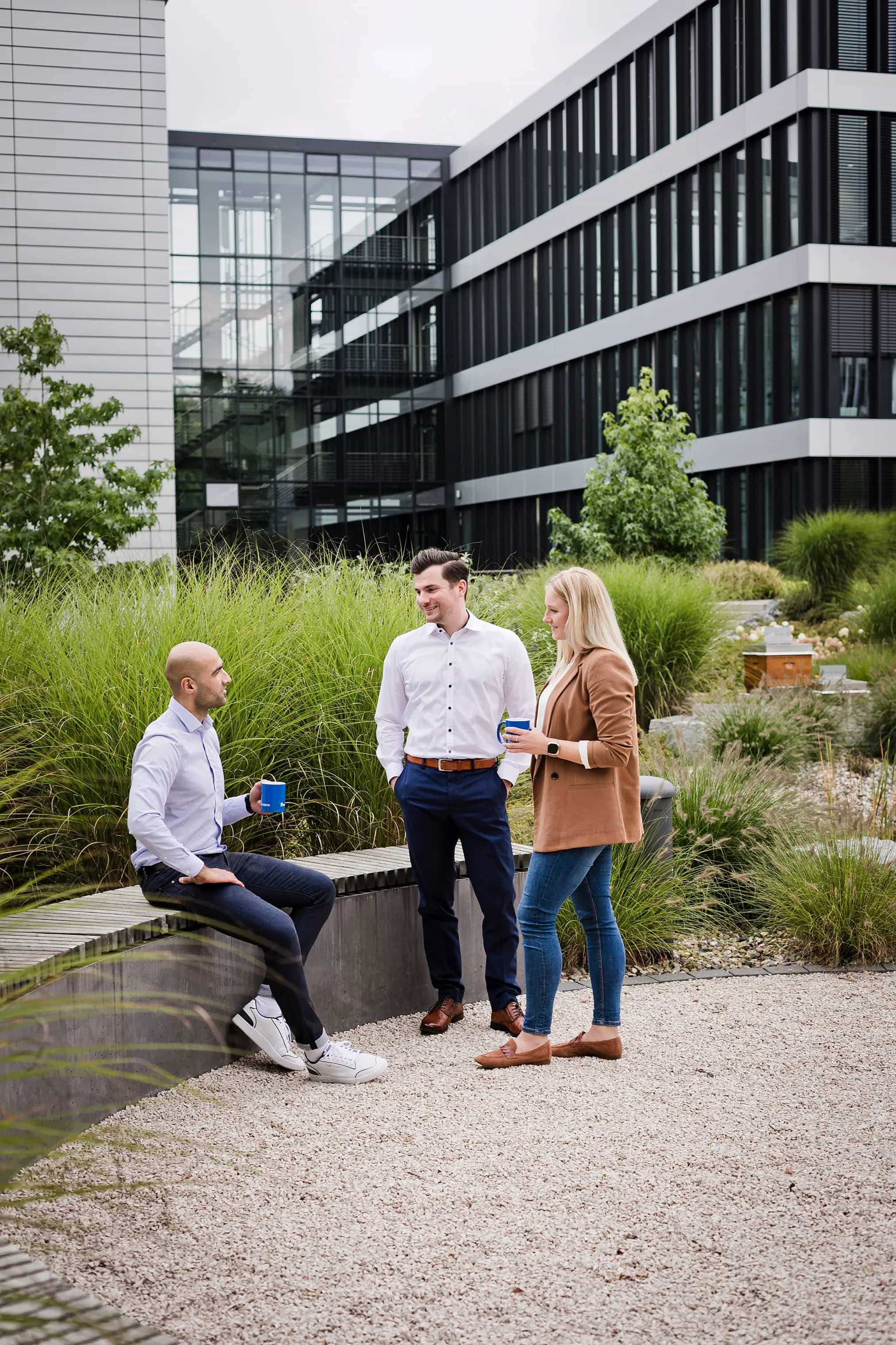 Trzy osoby w rozprzestrzenianiu się w nowoczesnym kantoorruimte buiten met groene planten op de achtergrond.